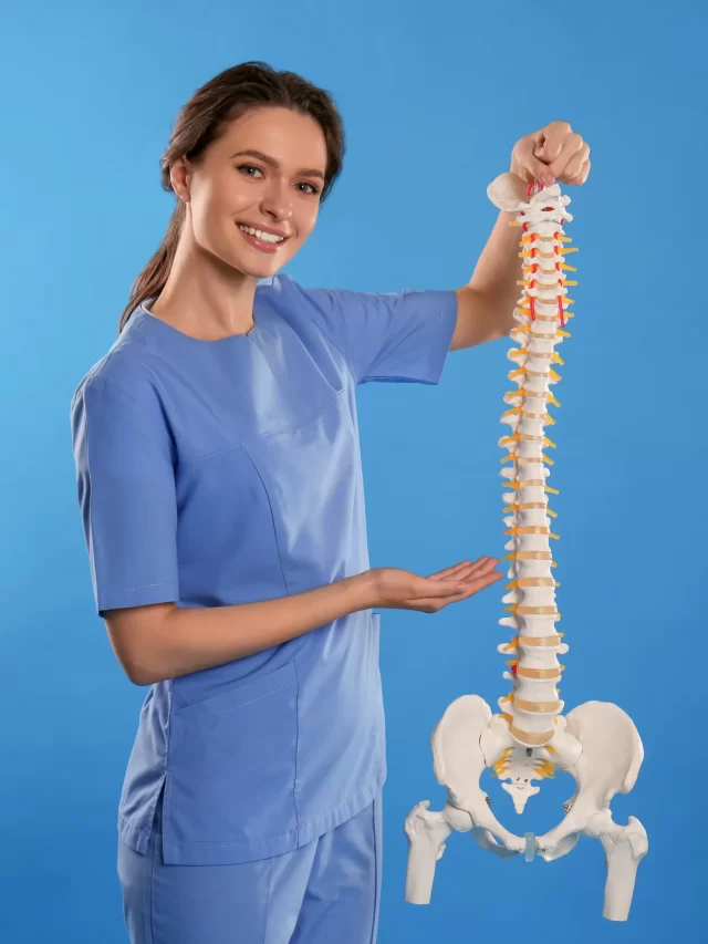 female-orthopedist-with-human-spine-model-against-blue-background